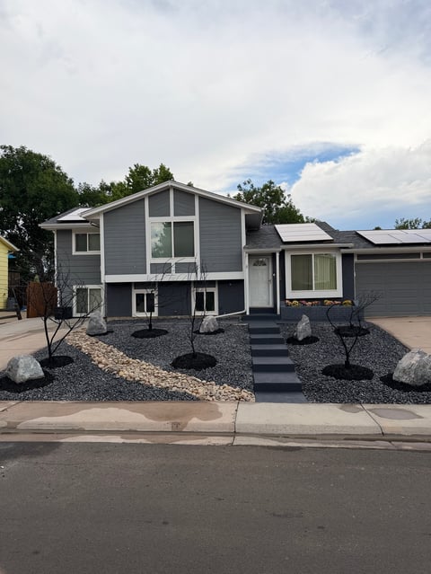 Modern two-story gray house with large windows and gravel landscaping