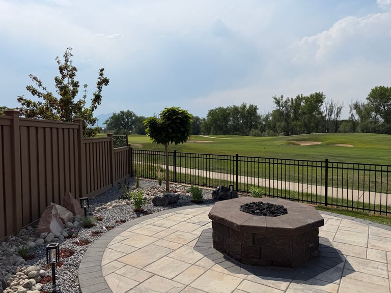 Backyard patio with fire pit overlooking golf course fairway with trees and clouds